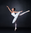Young ballerina dancing gracefully against black background