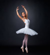 Pretty young ballerina performing against black background