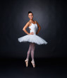 Pretty ballerina posing against black background