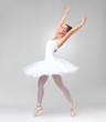 Young and beautiful ballerina dancing against white background