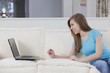 Teen girl looking at her laptop in her sofa at home