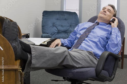Photo: Businessman on the phone with feet in his desk Businessman on the phone with feet in his desk