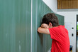 Young man leaning his head against a blackboard