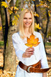 Foto: Happy woman holding leaf in the autumn colored park Happy woman holding leaf in the autumn colored park