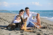 happy family playing with dog on beach