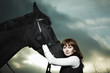 Beautiful young woman with a black horse