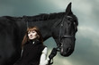 Beautiful young woman with a black horse