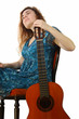 Frau mit akustischer Gitarre guckt verträumt nach Oben