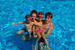 Happy family of four having fun in swimming pool