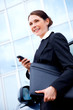 Young business woman outside with mobile phone, smiling