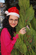 YOUNG SMILING SANTA WOMAN NEAR CHRISTMAS TREE