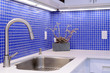 Kitchen sink, white counter with chrome faucet and blue tile wal