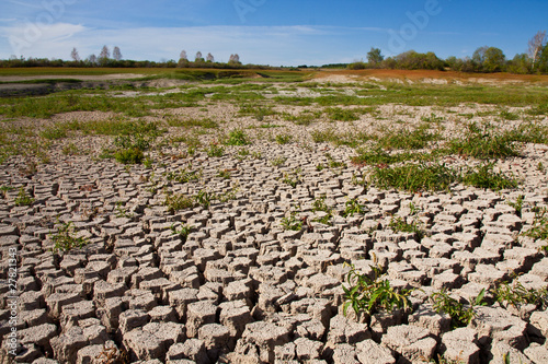Photo: Dried and cracked soil under blue sky Dried and cracked soil under blue sky