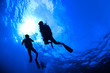 Scuba Divers in silhouet with sunburst on blue background