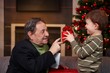 Small boy giving present to grandfather at christmas