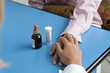 Closeup of doctor's hand holding patient's hand with medicine on table