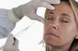 Hand holding botox syringe to woman's face