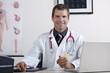 Doctor in his office with circulatory system chart and laptop