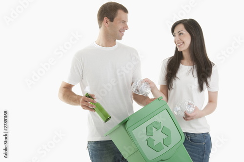 Photo: Couple throwing glass and plastic bottles in the recycling bin Couple throwing glass and plastic bottles in the recycling bin