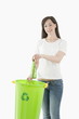 Young woman throwing glass bottle in the recycling bin