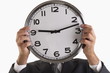 Man holding clock in front of his face