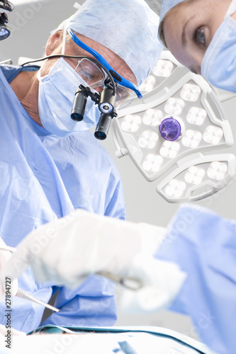 Foto: Concentrating surgeons performing operation in operating room Concentrating surgeons performing operation in operating room