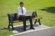 Businessman sitting on bench with laptop