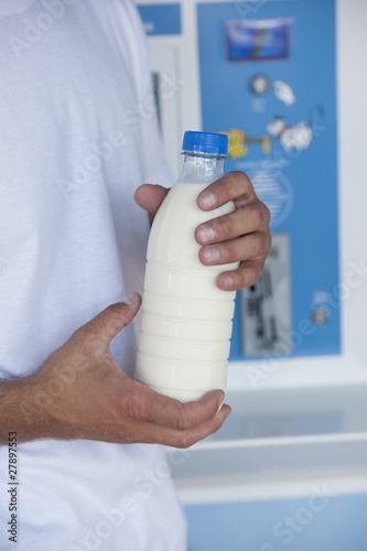 Photo: Closeup of man's hands holding milk bottle at cooler Closeup of man's hands holding milk bottle at cooler