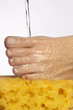Water pouring onto a woman's foot, resting on a yellow sponge