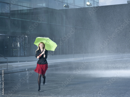 Photo: A young woman holding a green umbrella in the rain A young woman holding a green umbrella in the rain