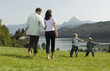 A family walking through the grass, children playing