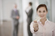 A businesswoman holding a piece of a jigsaw, two businessmen in the background