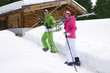 Couple standing in snow near lodge with skis
