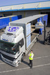 Worker near forklift loading semi-truck on loading dock