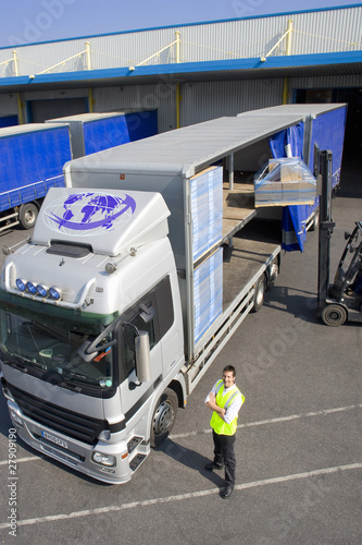 Foto: Worker near forklift loading semi-truck on loading dock Worker near forklift loading semi-truck on loading dock