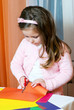 Little girl сut figures from a colour paper