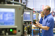 Foto: Worker operating computer controlled machinery in factory that manufactures aluminium light fittings Worker operating computer controlled machinery in factory that manufactures aluminium light fittings