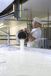 Photo: Cheese maker mixing rennet with milk in vat to begin cheddar cheese making process Cheese maker mixing rennet with milk in vat to begin cheddar cheese making process