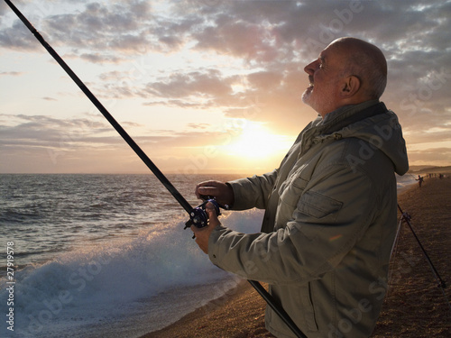 Photo: Senior man fishing in ocean at sunset Senior man fishing in ocean at sunset