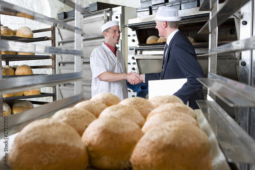 Foto: Inspector shaking hands with baker in bakery Inspector shaking hands with baker in bakery
