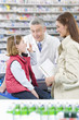 Daughter taking asthma inhaler as mother and pharmacist watch