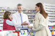 Pharmacist talking to mother about cold medicine in pharmacy
