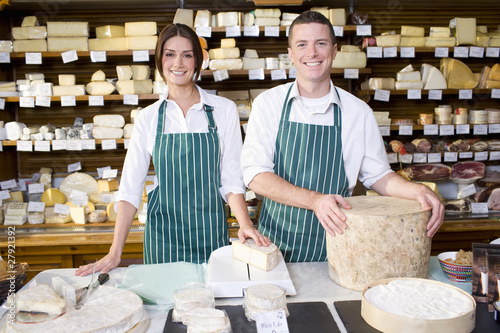 Photo: Salespeople standing at counter with cheese in cheese shop Salespeople standing at counter with cheese in cheese shop