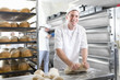 Baker kneading bread dough in bakery