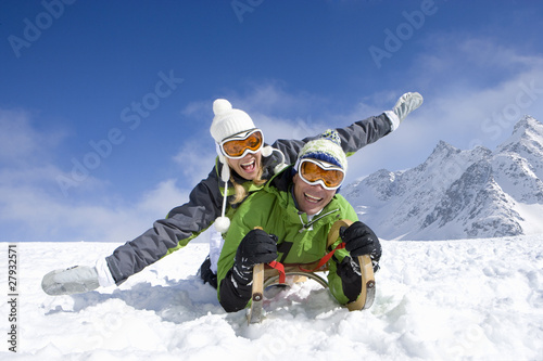 Foto: Couple laying on sled in snow on mountain top Couple laying on sled in snow on mountain top