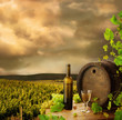 Wine, barrel and vine on background of early evening vineyard