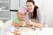 Cute daughter and mother showing a cookie in form of a man
