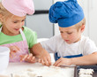 Young brother and sister kneading a dough to make cakes