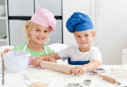 Photo: Happy brother and sister preparing a dough standing in the kitch Happy brother and sister preparing a dough standing in the kitch