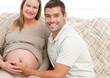 Happy future mom and dad relaxing in their living room